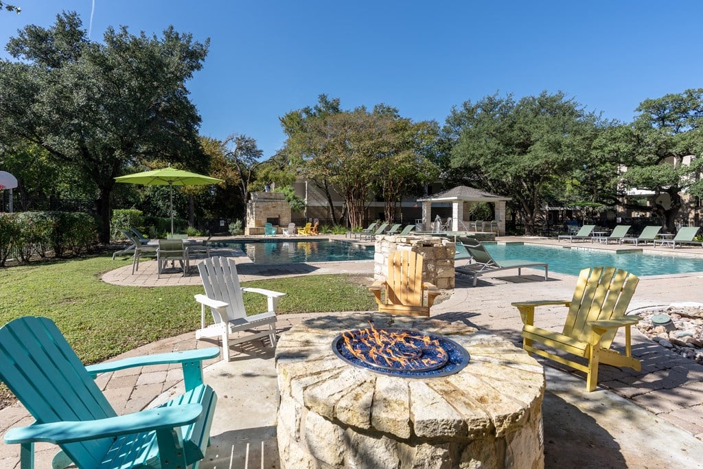 A fire pit sits in the middle of a patio surrounded by chairs.